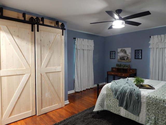 bedroom with hardwood / wood-style flooring, ceiling fan, and a barn door