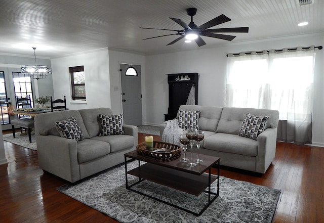 living room with crown molding, dark hardwood / wood-style flooring, a healthy amount of sunlight, and ceiling fan with notable chandelier