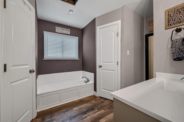 bathroom featuring a tub to relax in, a textured ceiling, hardwood / wood-style flooring, and sink