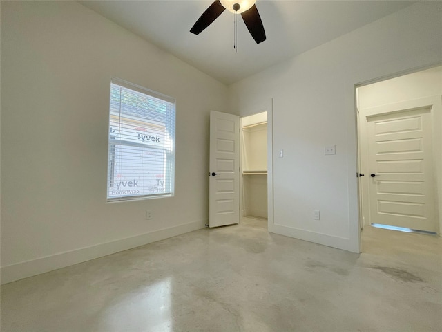 unfurnished bedroom featuring a walk in closet, a closet, and ceiling fan