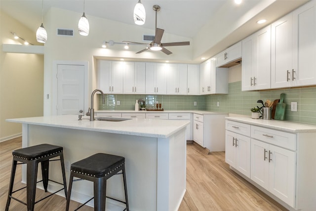 kitchen with backsplash, sink, light hardwood / wood-style flooring, ceiling fan, and white cabinetry