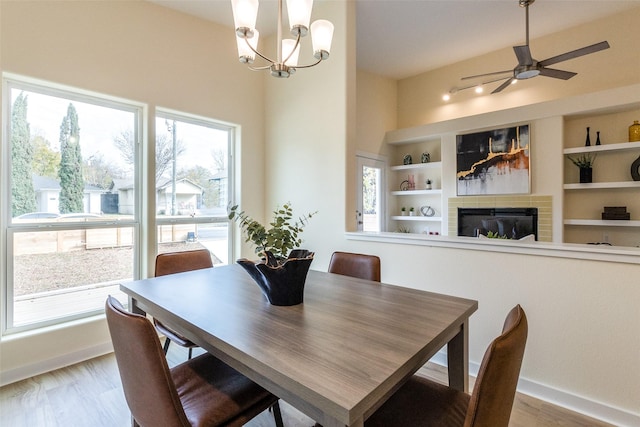 dining room featuring wood-type flooring, ceiling fan with notable chandelier, and built in features