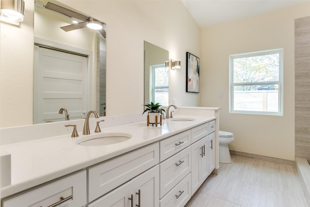 bathroom with tile patterned floors, vanity, toilet, and a wealth of natural light