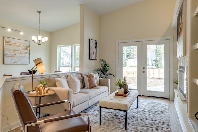 living room with french doors, an inviting chandelier, light hardwood / wood-style flooring, and a healthy amount of sunlight