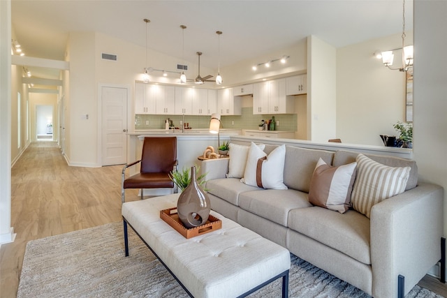 living room with a chandelier, light hardwood / wood-style floors, and vaulted ceiling