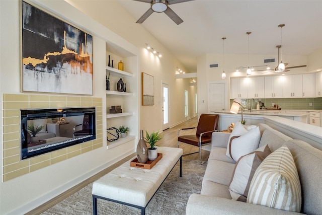 living room featuring ceiling fan, built in features, sink, and light hardwood / wood-style flooring