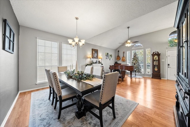 dining area with ceiling fan with notable chandelier, vaulted ceiling, light hardwood / wood-style floors, and a textured ceiling