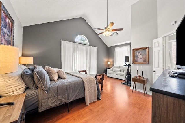 bedroom with hardwood / wood-style flooring, high vaulted ceiling, and ceiling fan