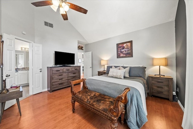 bedroom featuring ceiling fan, high vaulted ceiling, ensuite bathroom, and light wood-type flooring