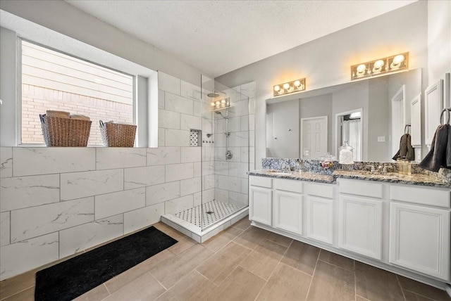 bathroom featuring vanity, a textured ceiling, and a tile shower