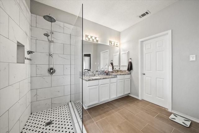 bathroom featuring vanity, a textured ceiling, and tiled shower