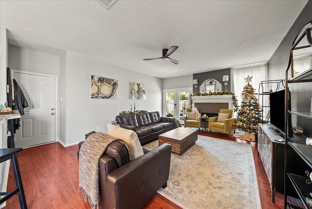 living room featuring a fireplace, dark hardwood / wood-style flooring, ceiling fan, a textured ceiling, and french doors