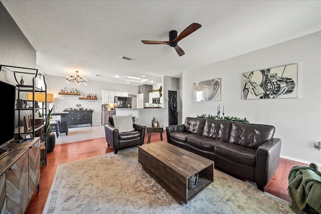 living room featuring ceiling fan, light hardwood / wood-style flooring, and a textured ceiling