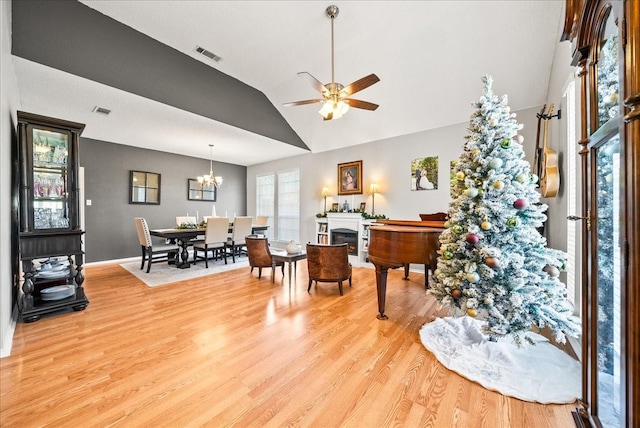 interior space with vaulted ceiling, ceiling fan with notable chandelier, and light wood-type flooring