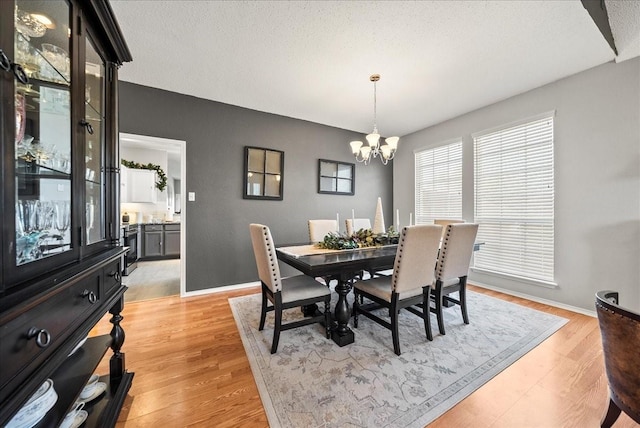 dining area featuring a textured ceiling, light hardwood / wood-style flooring, and a notable chandelier