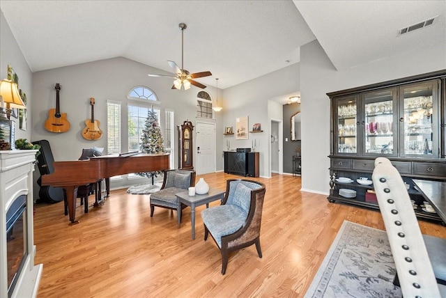 living room featuring ceiling fan, high vaulted ceiling, and light wood-type flooring