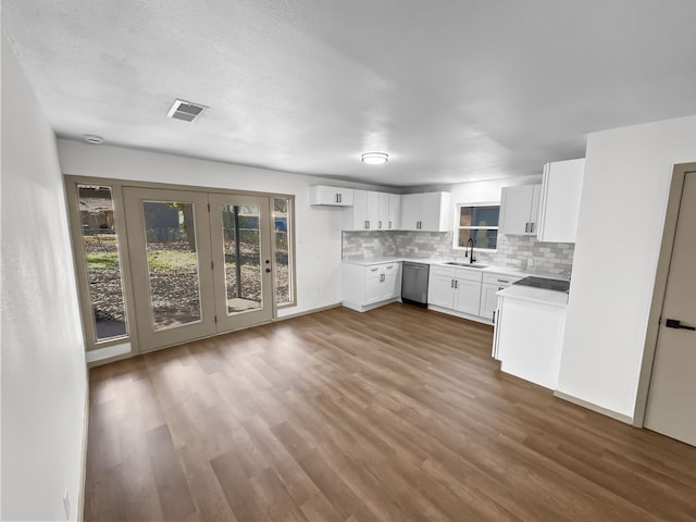 kitchen with tasteful backsplash, stainless steel dishwasher, sink, white cabinets, and dark hardwood / wood-style floors