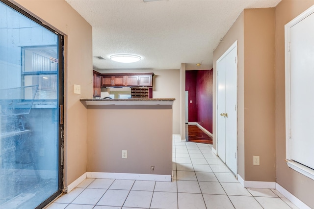 kitchen featuring kitchen peninsula, light tile patterned floors, and a textured ceiling