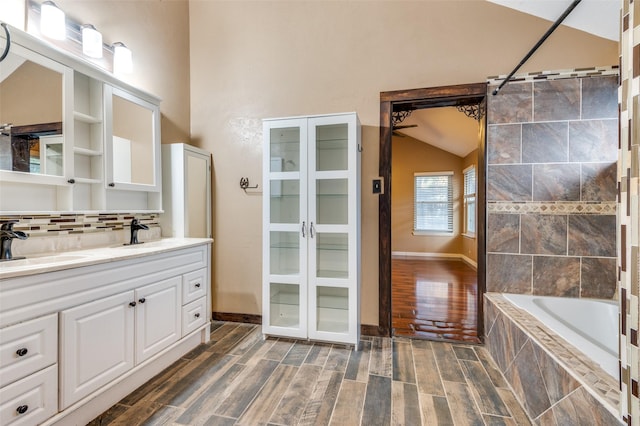 bathroom featuring hardwood / wood-style floors, vanity, tiled shower / bath combo, and lofted ceiling