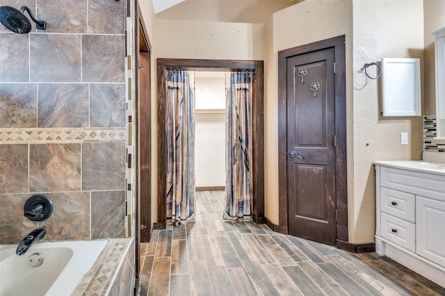 bathroom with hardwood / wood-style floors, vanity, and tiled shower / bath combo