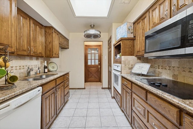 kitchen with white appliances, sink, light tile patterned floors, and tasteful backsplash