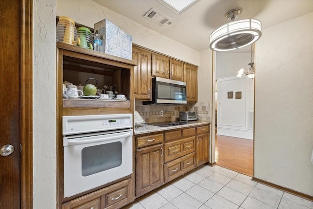 kitchen with decorative backsplash, light tile patterned floors, black electric cooktop, and white oven