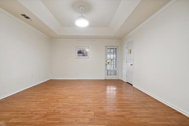 spare room featuring light wood-type flooring, crown molding, and a tray ceiling