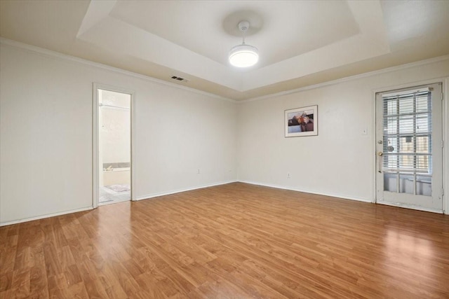 unfurnished room featuring wood-type flooring, ornamental molding, and a tray ceiling