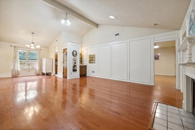 unfurnished living room featuring lofted ceiling with beams, a chandelier, a textured ceiling, and hardwood / wood-style flooring