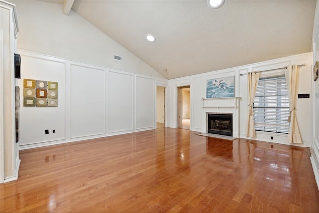 unfurnished living room with beamed ceiling, hardwood / wood-style flooring, and high vaulted ceiling