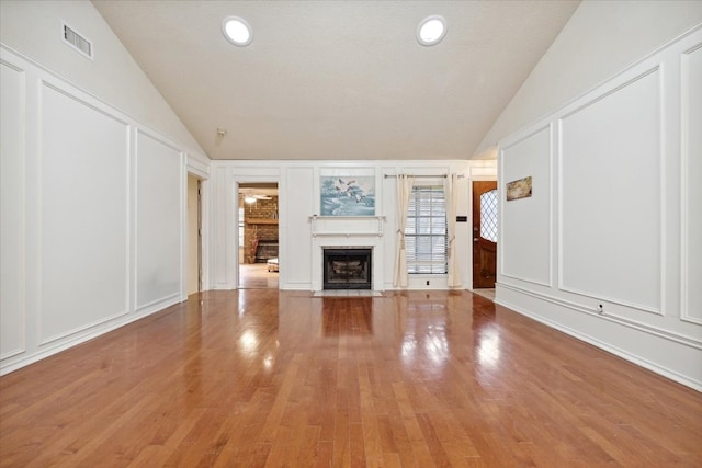 unfurnished living room with wood-type flooring, a textured ceiling, and vaulted ceiling