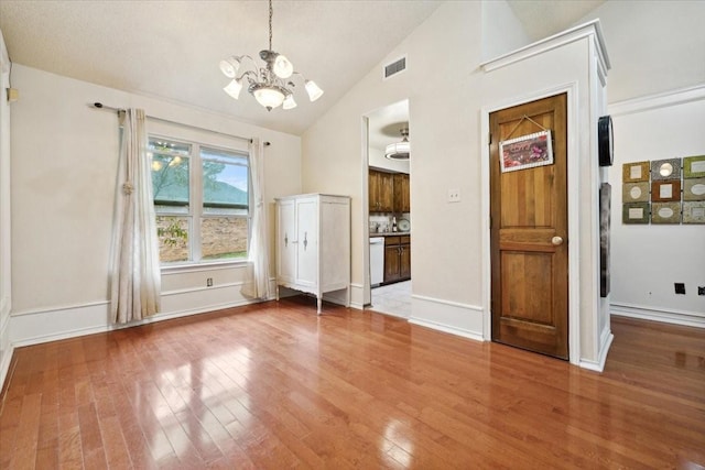 unfurnished dining area with lofted ceiling, wood-type flooring, and an inviting chandelier