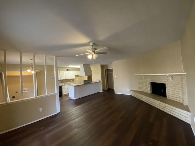 unfurnished living room featuring a fireplace, dark wood-type flooring, and ceiling fan with notable chandelier