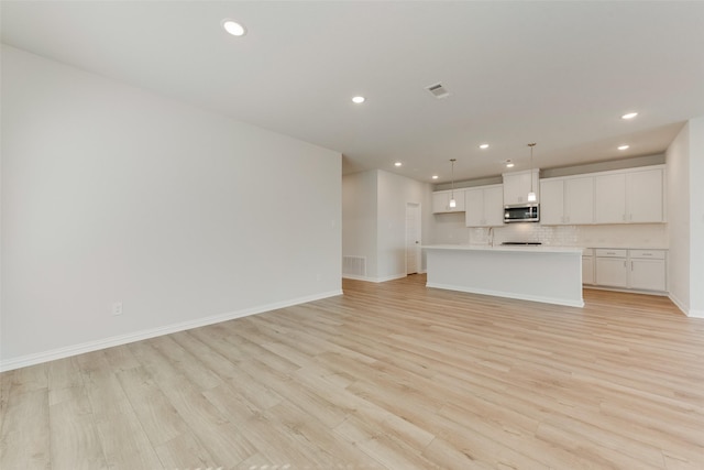 unfurnished living room with sink and light hardwood / wood-style floors