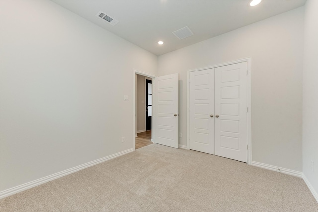 unfurnished bedroom featuring a closet and light carpet