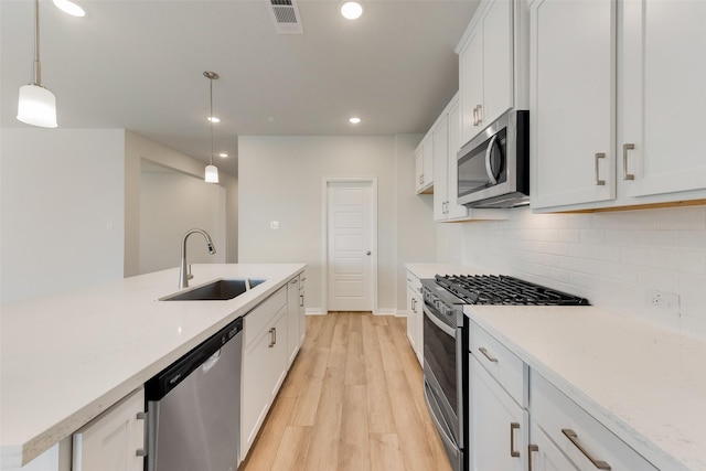 kitchen with sink, decorative light fixtures, white cabinets, and appliances with stainless steel finishes