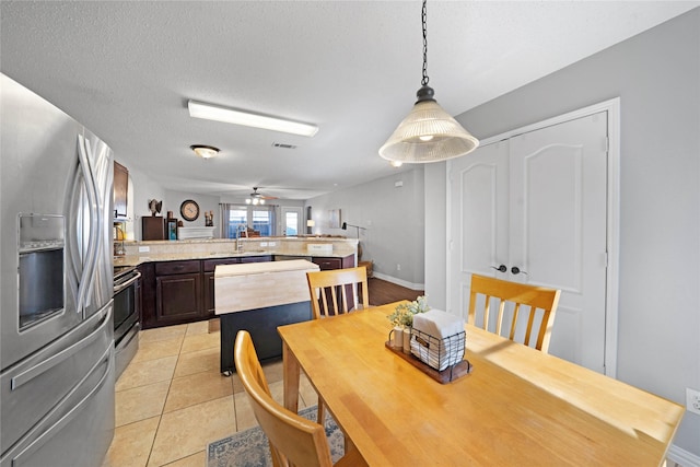 tiled dining space featuring ceiling fan, sink, and a textured ceiling