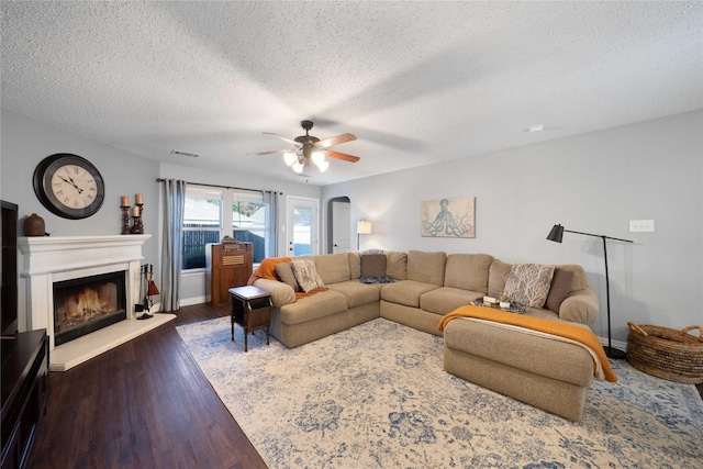 living room with a textured ceiling, dark hardwood / wood-style floors, and ceiling fan