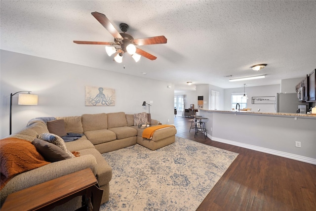 living room featuring sink, ceiling fan, dark hardwood / wood-style flooring, and a textured ceiling