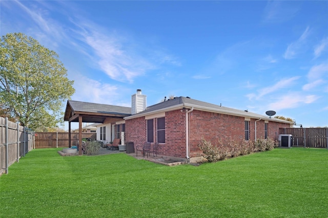 back of house with central AC unit and a yard