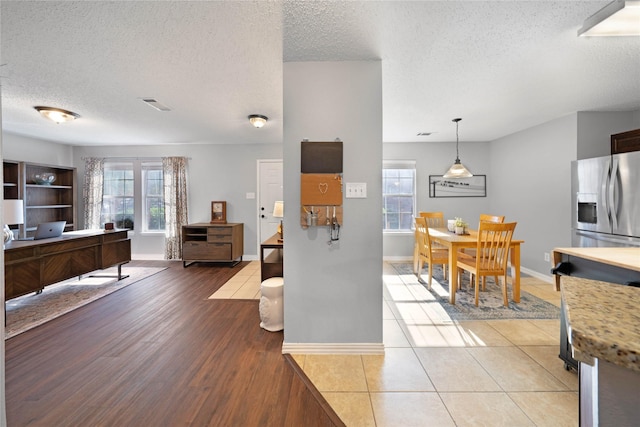 kitchen featuring stainless steel refrigerator with ice dispenser, a textured ceiling, hardwood / wood-style flooring, and hanging light fixtures