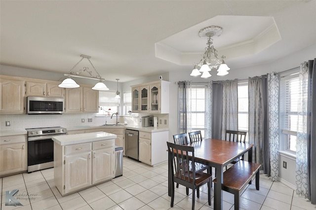 kitchen featuring sink, decorative light fixtures, a center island, a raised ceiling, and stainless steel appliances