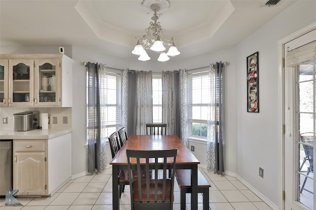 tiled dining room with a notable chandelier, a tray ceiling, and ornamental molding