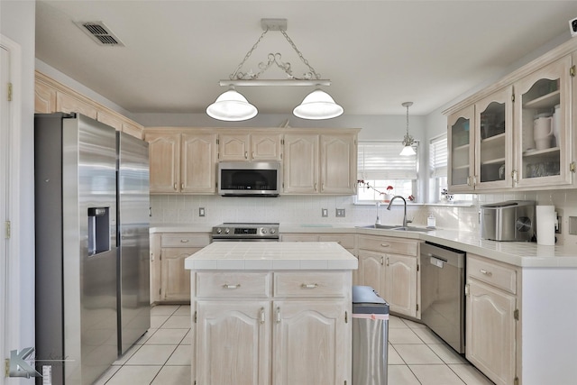 kitchen with stainless steel appliances, a kitchen island, sink, and tile counters