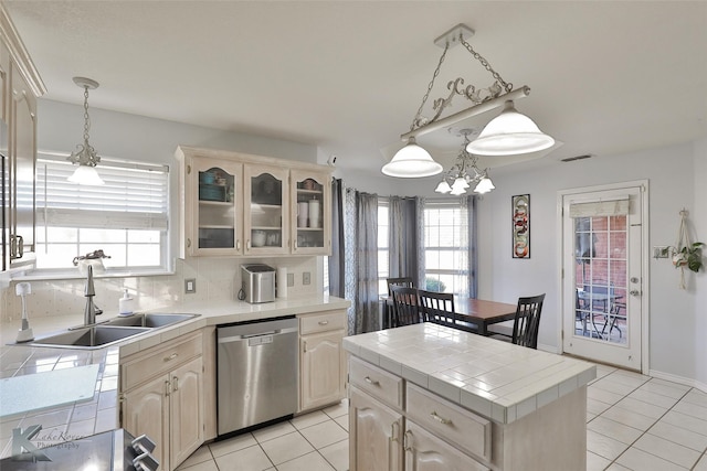 kitchen featuring a kitchen island, dishwasher, sink, backsplash, and tile counters