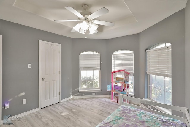 unfurnished bedroom featuring light hardwood / wood-style flooring, a raised ceiling, and ceiling fan