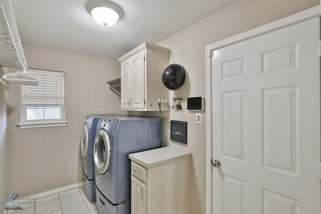 washroom featuring cabinets, washing machine and dryer, a textured ceiling, and light tile patterned floors