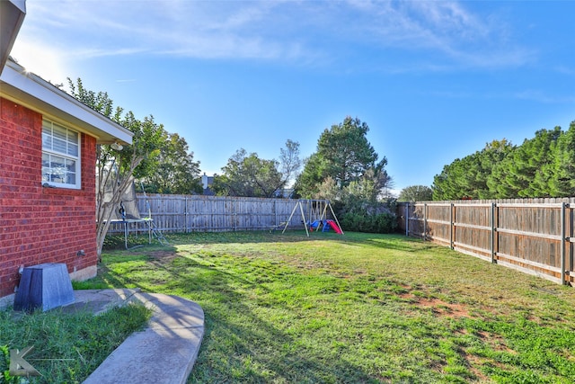 view of yard with a trampoline and a playground