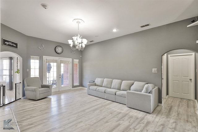 living room with an inviting chandelier, light wood-type flooring, and french doors