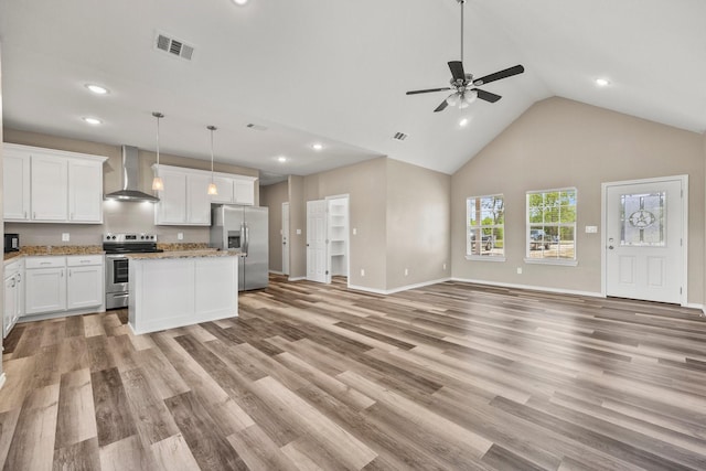 interior space with appliances with stainless steel finishes, visible vents, open floor plan, wall chimney exhaust hood, and a ceiling fan